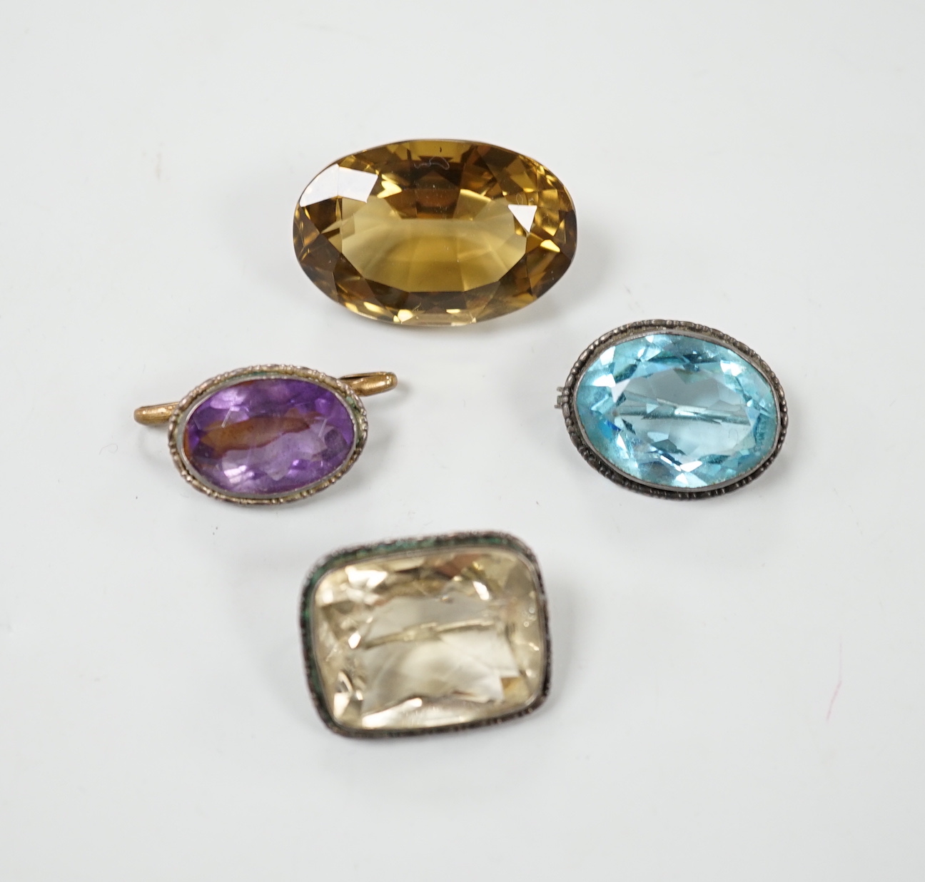 A large unmounted cut citrine, together with a mounted amethyst brooch and two other gem set brooches including pale citrine and blue paste.